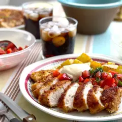 Krispiga kycklingfiléer med cajun krydda, serverade med rostade potatisar, tomatsalsa och en krämig sås. En härlig måltid!