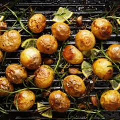 Gyllene, krispiga småpotatisar som grillas med rosmarin, vitlök och citronklyftor på en grillpanna. En härlig rätt att grilla potatis till!