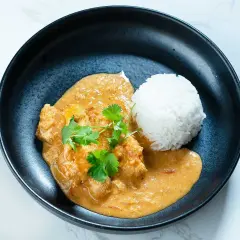 En krämig butter chicken med ris och färsk koriander.