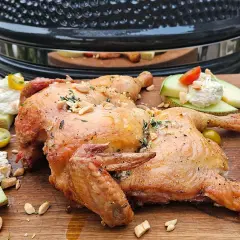 Hel kyckling på en skärbräda, perfekt för ett somrigt grill recept. Serveras med melon, färskost och tomater.