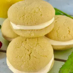 Små, runda kakor med krämig fyllning, perfekt för ett enkelt lemoncurd recept. En gul citron syns i bakgrunden.