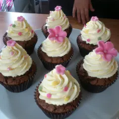 Sju chokladmuffins med fluffig vit choklad frosting, dekorerade med rosa blommor och strössel. Perfekt för ett kalas!
