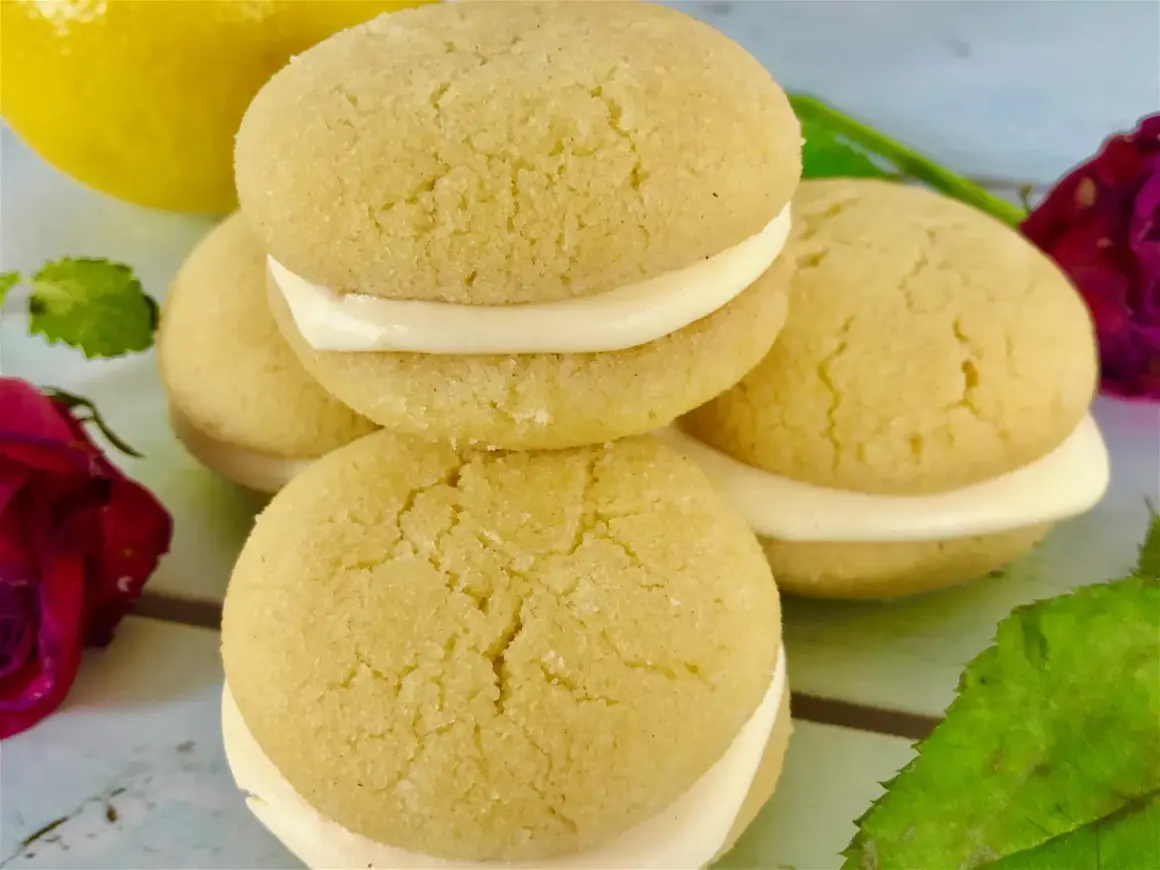 Små, runda kakor med krämig fyllning, perfekt för ett enkelt lemoncurd recept. En gul citron syns i bakgrunden.