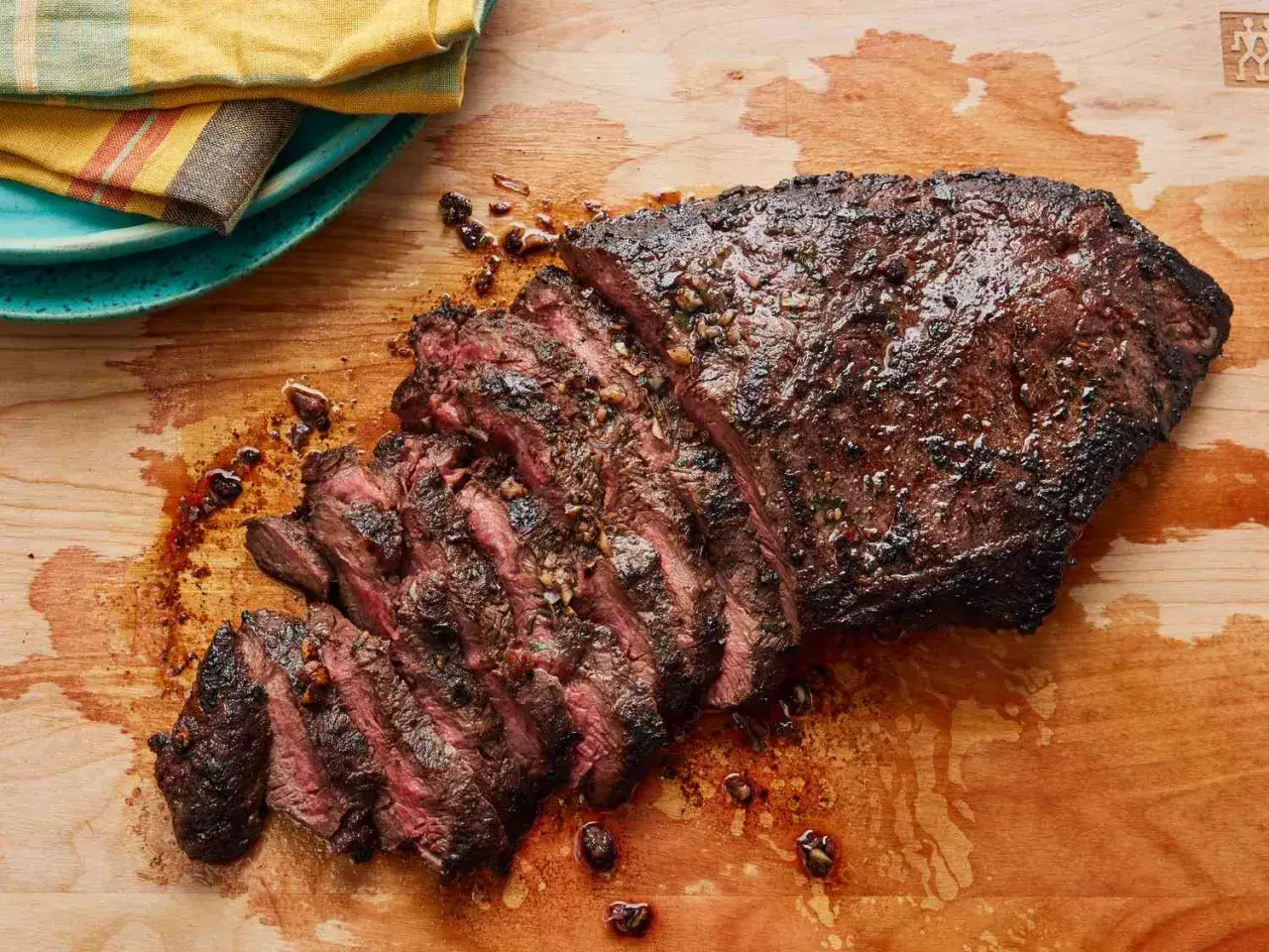 En saftig, skivad flat iron steak med en härlig stekyta, serverad på en träskärbräda med lite köttsaft.