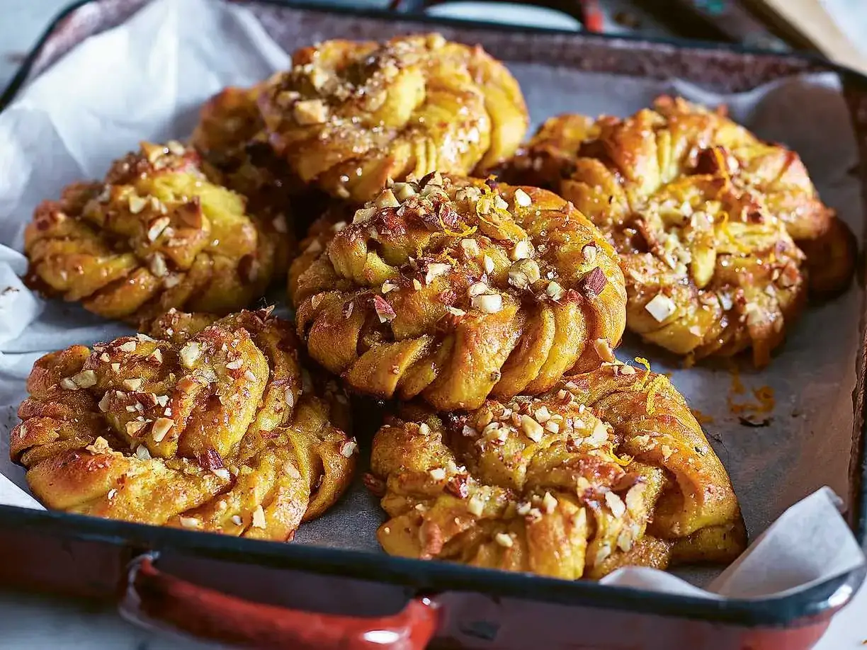 Nybakade saffransbullar med hackade nötter och apelsinzest, redo att avnjutas. Perfekt för att baka med Frida saffran.