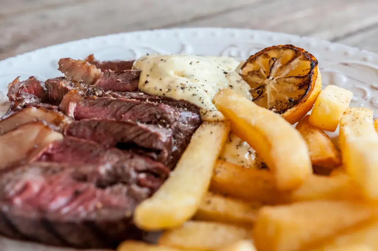 Skivad biff med pommes frites och en klick falsk bearnaisesås kall, toppad med en grillad citronklyfta.